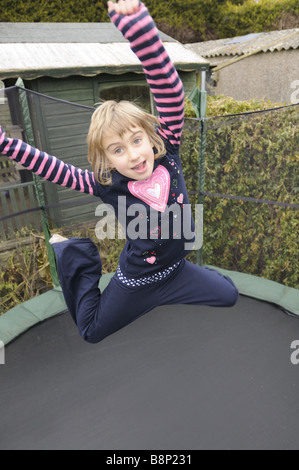 Un bambino di sei anni ragazza rimbalza su un trampolino Foto Stock