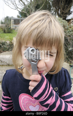 Un bambino di sei anni bambina gioca con una chiave regolabile Foto Stock