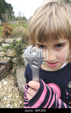 Un bambino di sei anni bambina gioca con una chiave regolabile Foto Stock