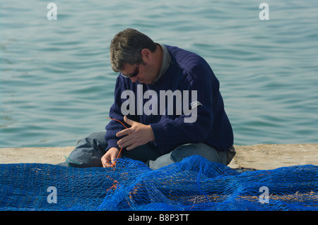 Fisherman uomo rammendo che ripara le sue reti da pesca a Santa Pola Spagna Foto Stock