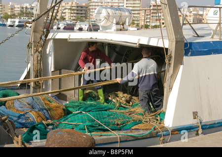 I pescatori operanti Winching nel loro funi su un deck di Peschereccio di Santa Pola Spagna Foto Stock