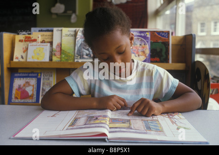 Scuola elementare anni '1980 Regno Unito. Ragazza britannica nera che legge un libro da solo concentrando Londra Inghilterra 1980 HOMER SYKES Foto Stock