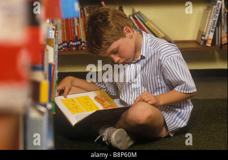 Scuola elementare 1980 Regno Unito. Ragazzo che legge un libro da solo concentrando Londra Inghilterra 1980 OMERO SYKES Foto Stock