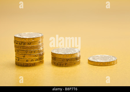 Pile decrescenti di £ 1 una libbra di monete sterling su fondo oro Foto Stock