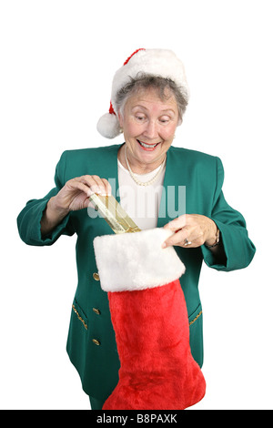 Un entusiasta senior donna aprendo la sua calza di Natale isolato su bianco Foto Stock