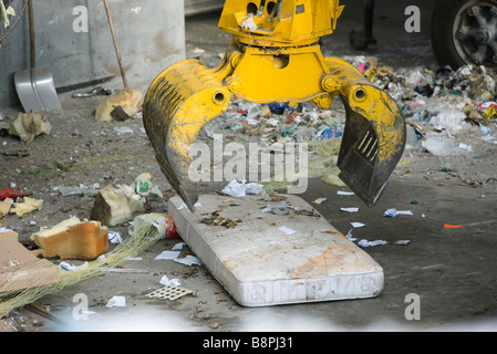 La benna mordente di prelevare il materasso in discarica di rifiuti Foto Stock