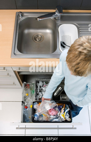 Bambino immissione nel contenitore di plastica nel cestino può piuttosto che vicino a cassonetti per il riciclaggio Foto Stock