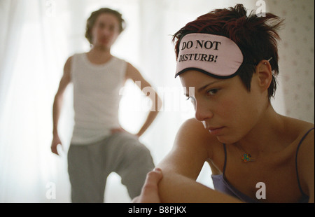 Giovane donna broncio, man standing in background con mano su hip Foto Stock