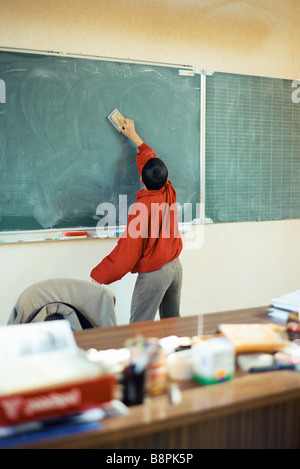 Ragazzo la cancellazione di lavagna in aula Foto Stock