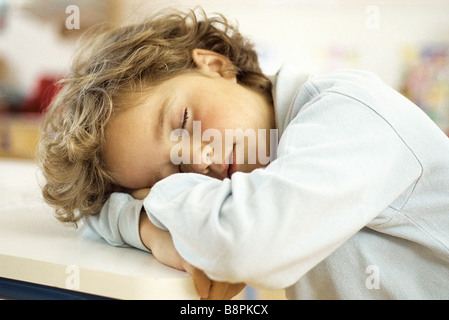 Bambina sonnecchiare con testa sulla scrivania Foto Stock