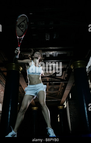 Tennista donna che pratica di notte in un ambiente urbano praticando sotto gli archi ferroviari Londra, Regno Unito Foto Stock