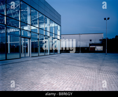 Vuoto area parcheggio vuoto e show room, crepuscolo, area vuota, linee grafiche. Edificio, blocco di pavimentazione, ombre. Presto la sera. Foto Stock