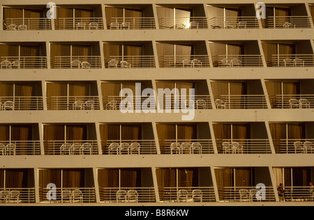 Linee grafiche di una fila di balconi al tramonto in Elat in Israele, contrasto, giallo luce calda, sedie. Forme, schemi di ripetizione. Foto Stock
