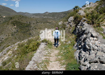 Donna escursionista sui ripidi e antica, Mozarabo trail, Vall de Laguart, Benimaurell, Provincia di Alicante, Comunidad Valenciana, Spagna Foto Stock