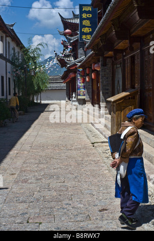 Una donna Naxi in abito tradizionale in una strada di Lijiang, nella provincia dello Yunnan in Cina. Foto Stock