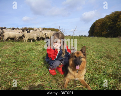 Gli animali domestici delle specie ovina (Ovis ammon f. aries), pastore figlia con sheepdog nella parte anteriore del gregge di pecore, Germania nord Rhine-Westphali Foto Stock