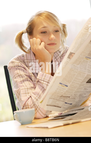 Giovane donna con tazza di caffè e quotidiano gratuito al mattino, Germania Foto Stock