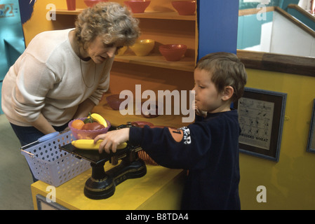 La scuola materna di ragazzo giocando in un giocattolo negozio di alimentari Foto Stock