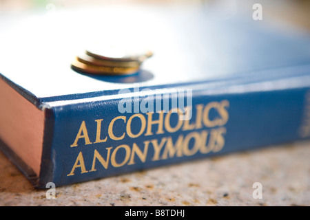 Il grande libro degli alcolisti anonimi con una pila di sobrietà chips, mostrando come molti anni sobrio, materiale di lettura Foto Stock