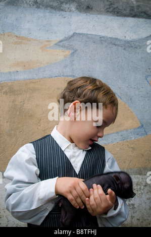 Giovane ragazzo infantile azienda appena nata vaso panciuto maialino Foto Stock