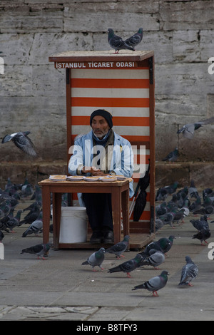 Venditore di biglietti combattendo i piccioni presso la nuova moschea di Istanbul in Turchia. Foto Stock