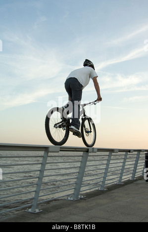 Ragazzo equitazione mountain bike sulla parte superiore del corrimano sul lungomare dal fiume Humber, East Yorkshire, Regno Unito Foto Stock