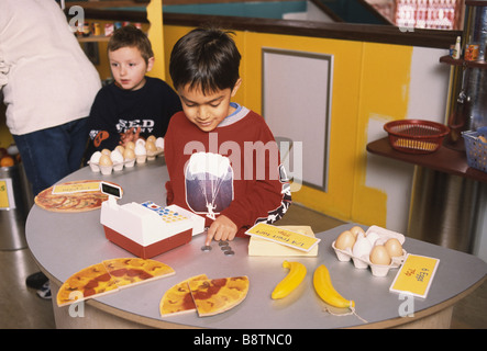 Due la scuola materna di ragazzi giocare in un giocattolo negozio di alimentari Foto Stock