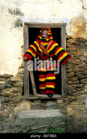 Un uomo vestito con una tradizione 'Caretos' costume incorniciato in una casa colonica porta durante il carnevale di celebrazioni in Podence, Portogallo Foto Stock