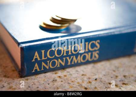 Il grande libro degli alcolisti anonimi con una pila di sobrietà chips, mostrando come molti anni sobrio, materiale di lettura Foto Stock
