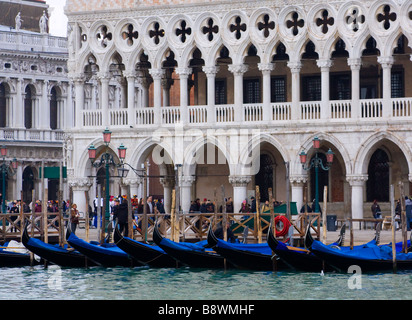 Palazzo Ducale visto da acqua, con una fila di gondole di fronte e la gente che camminava nelle vicinanze Foto Stock