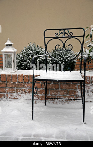 Rustico in ferro battuto giardino sedile e una lampada a luce coperchio lanterna con neve invernale Foto Stock