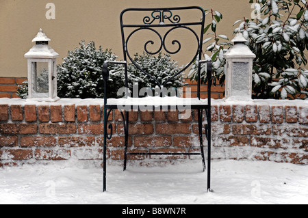 Rustico in ferro battuto giardino sedile e due lampade luci di lanterne lanterna copertura leggera con neve invernale Foto Stock