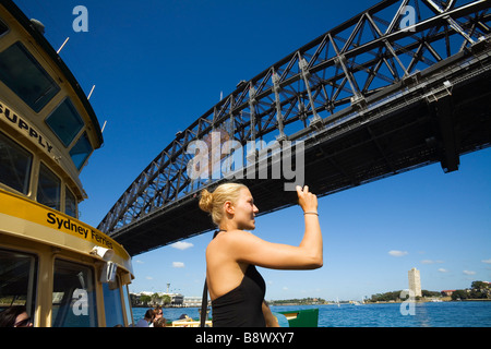 Una donna fotografa il Harbour Bridge su una crociera del porto. Sydney, Nuovo Galles del Sud, Australia Foto Stock