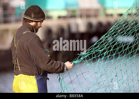 Mare del Nord i pescatori rammendo e riparazione di reti da pesca nel porto a Peterhead, Aberdeenshire, Scotland, Regno Unito Foto Stock