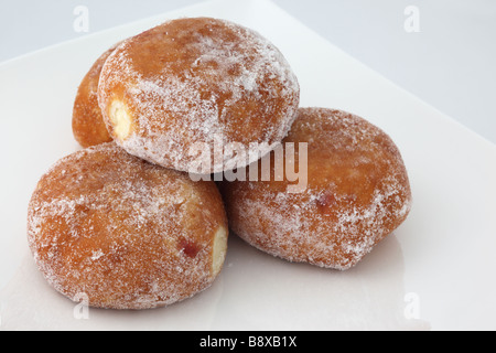 Primo piano di quattro ciambelle di confettura zuccherate fresche contro un sfondo bianco Foto Stock