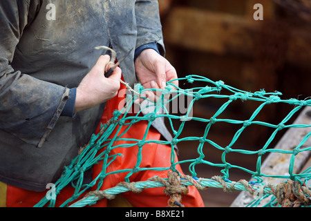 Mare del Nord i pescatori rammendo e riparazione di reti da pesca nel porto a Peterhead, Aberdeenshire, Scotland, Regno Unito Foto Stock