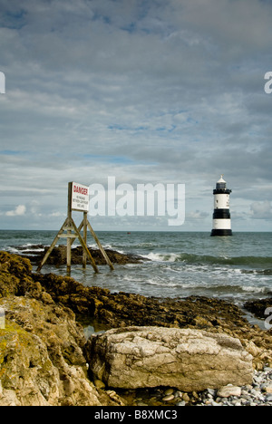 Una spiaggia rocciosa e Penmon faro, Anglesey, Galles. Regno Unito. Foto Stock