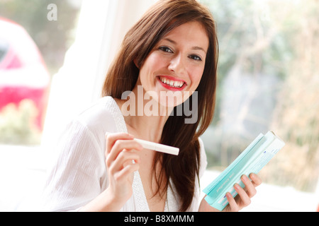 Donna felice con i risultati del test di gravidanza Foto Stock