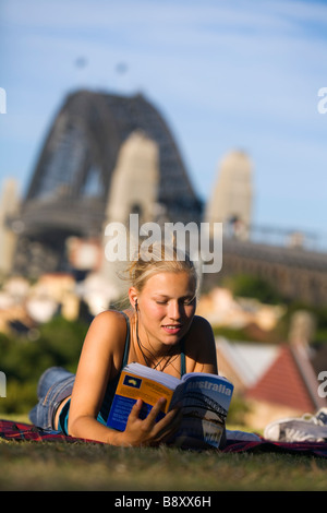 Una giovane donna legge un libro guida osservatorio sulla collina che si affaccia sul porto di Sydney. Sydney, Nuovo Galles del Sud, Australia Foto Stock