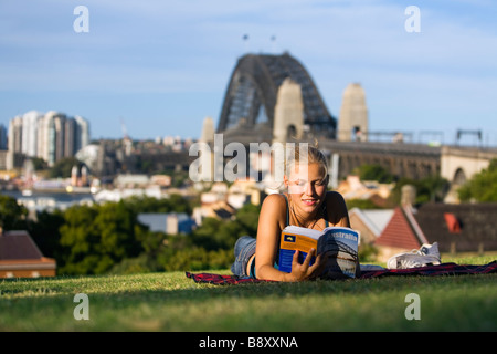 Una giovane donna legge un libro guida osservatorio sulla collina che si affaccia sul porto di Sydney. Sydney, Nuovo Galles del Sud, Australia Foto Stock