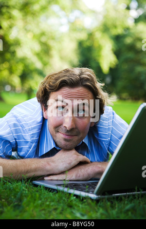 Un uomo con un computer portatile in un parco in Svezia. Foto Stock