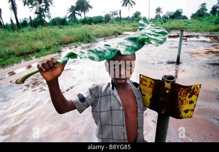 Nigeria: un ragazzo sorge oltre ad un segno di pericolo da un olio contaminato area in Ogoniland Foto Stock