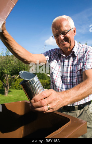 Un uomo anziano tenendo un stagno da un bidone della spazzatura in Svezia. Foto Stock