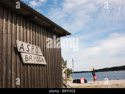 Una ragazza in piedi sulle sue mani su un molo nel arcipelago di Stoccolma in Svezia. Foto Stock