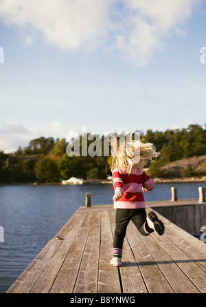 Una ragazza in esecuzione su un pontile arcipelago di Stoccolma in Svezia. Foto Stock