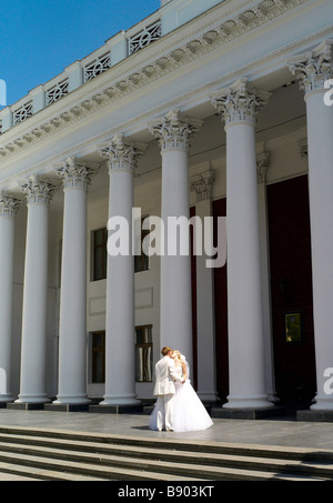 La sposa e lo sposo nel giorno del matrimonio sui passi di gli edifici civici in Odessa Ucraina Foto Stock