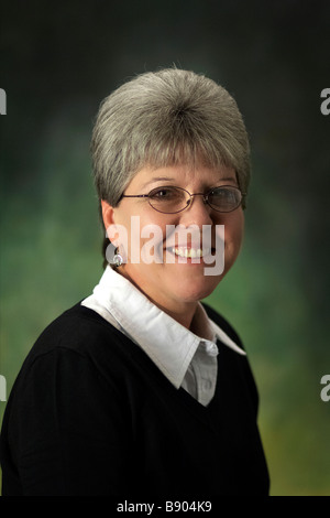 Una matura caucasian donna con i capelli grigi con gli occhiali e un maglione Foto Stock