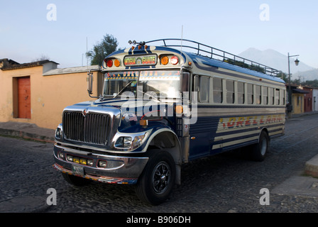 Un autobus pubblico "chicken bus' passando attraverso le strade coloniali di Antigua Guatemala, America Centrale Foto Stock