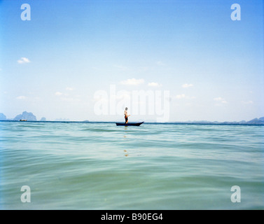 Un uomo in una piccola barca sul mare blu della Thailandia. Foto Stock