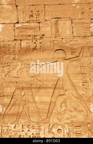 Rilievo del faraone Ramesse III uccidendo nemici scolpiti sulla parete del pilone di [Medinet Habu] Tempio mortuario, 'West Bank", Luxor, Egitto Foto Stock